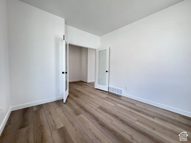 Wood-finish flooring, white walls, and French doors with frosted glass panels