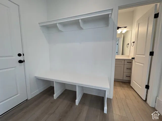Built-in bench with upper shelving, matte black door hardware, wood-finish flooring, and white interior doors