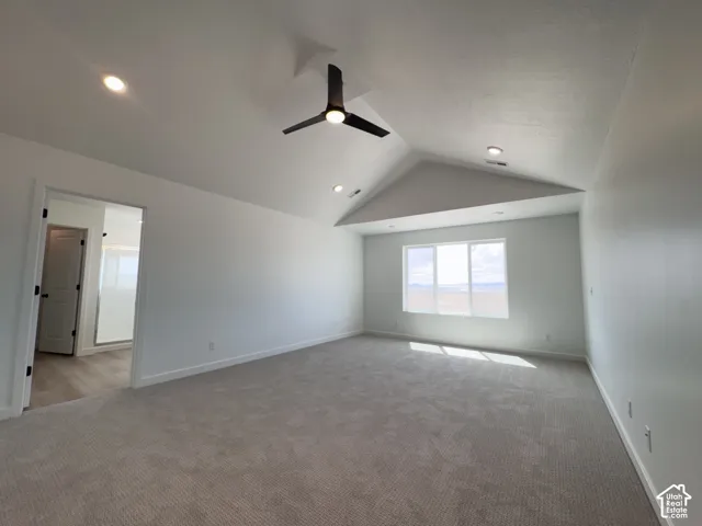 Vaulted ceiling with recessed lighting and contemporary ceiling fan, large windows, plush carpet flooring, and wood-finish flooring visible through doorway