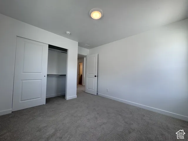 Neutral wall color, recessed ceiling light, paneled closet doors, built-in closet shelving, and gray carpet flooring