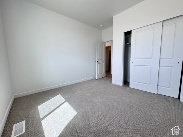 Neutral-toned carpet flooring, white walls, and a white sliding closet door