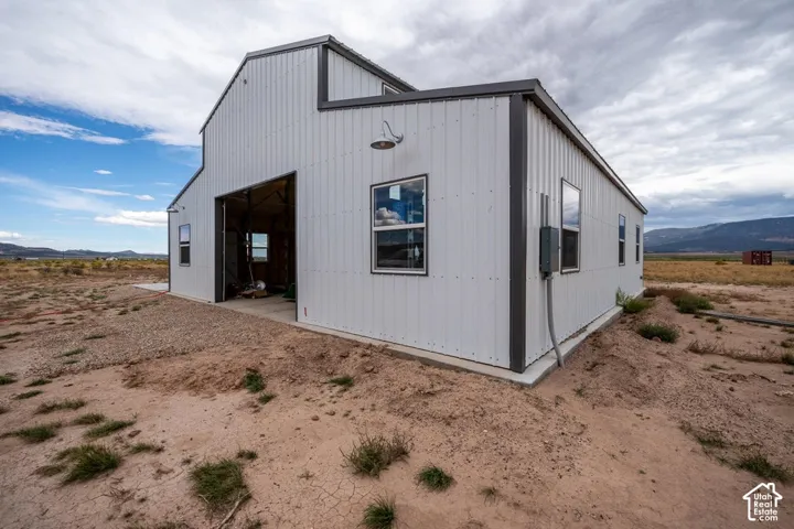 Corrugated metal exterior with dark trim accents, multiple windows, and a large roll-up door