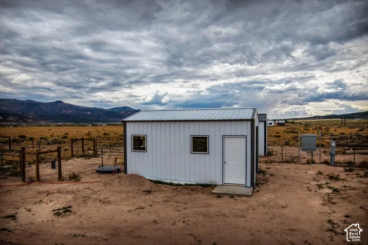 White metal outbuilding with a metal roof, two windows, and a white door