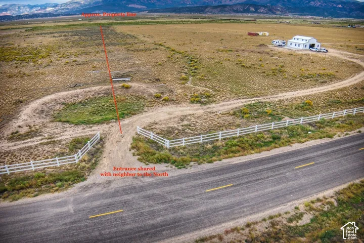 Expansive land parcel with unpaved access roads and a white fence bordering the main road