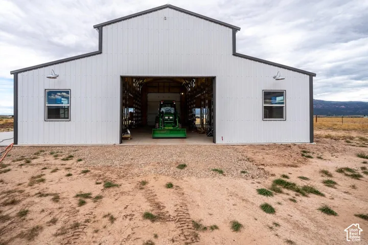 Expansive metal building featuring a large overhead door, white corrugated siding, dark trim, and two exterior wall-mounted light fixtures
