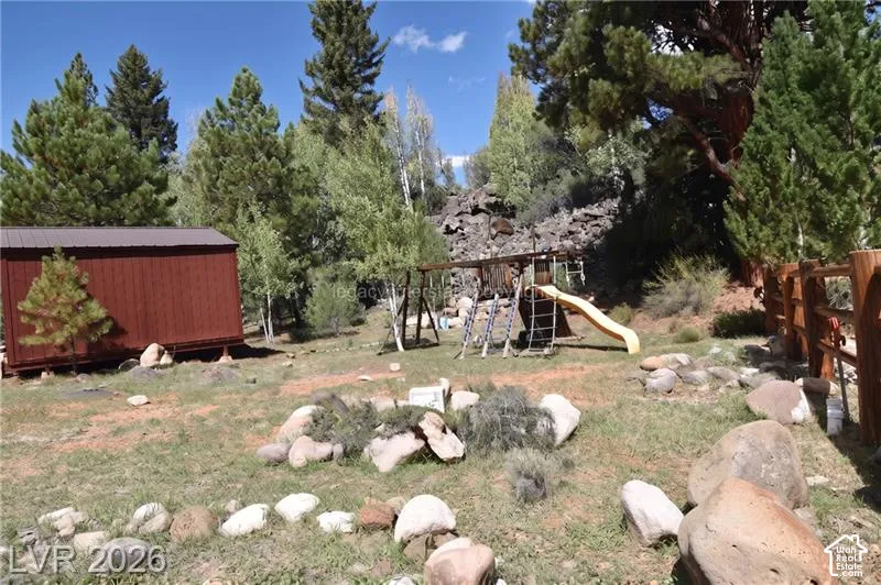 Expansive yard featuring natural rock landscaping, mature trees, and a wood privacy fence