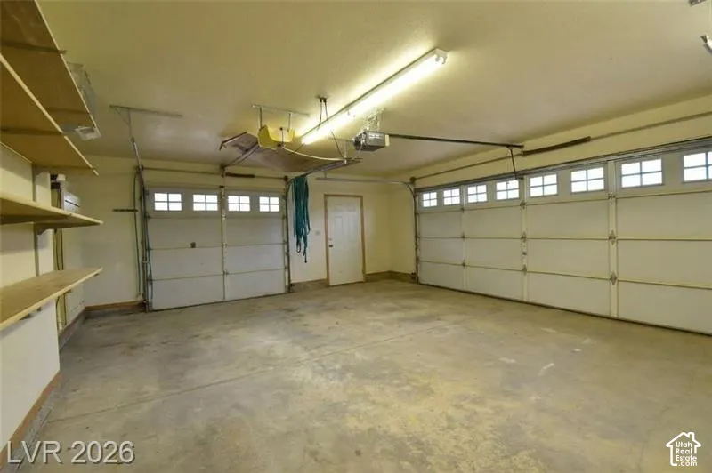 Dual garage doors with upper window panels, integrated shelving, and overhead fluorescent lighting