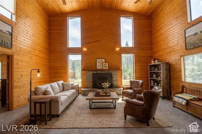 Vaulted wood-paneled ceilings, wood-paneled walls, stone fireplace with hearth, built-in wooden shelving, and multiple windows