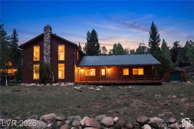 Wood-sided home with a stone chimney, multiple large windows, and a covered porch