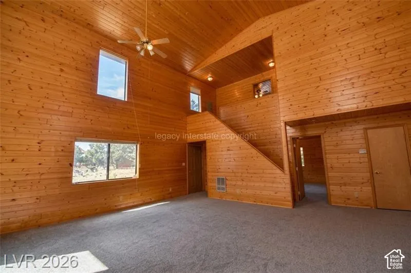Vaulted wood-paneled ceilings with ceiling fan, wood-paneled walls, multiple windows, and a built-in staircase