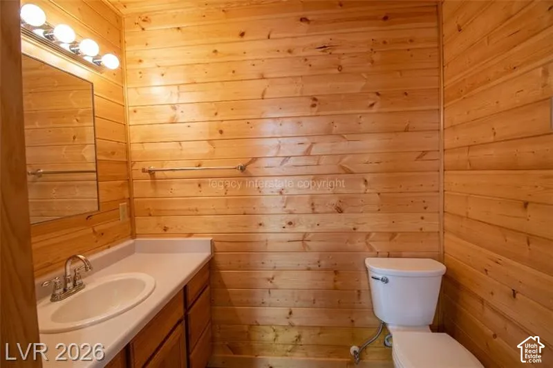 Wood-paneled walls featuring a vanity with an integrated sink, polished chrome faucet, and a wall-mounted mirror