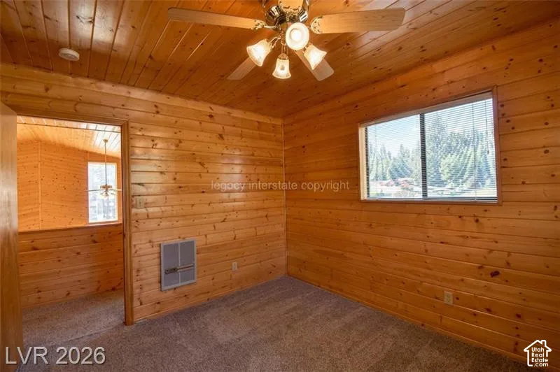 Wood-paneled walls and ceiling, wall-to-wall carpeting, and a ceiling fan with integrated lighting