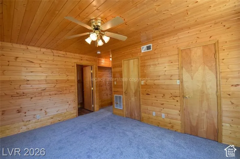 Wood paneling throughout, wood plank ceiling, light-toned wood doors, and a ceiling fan with integrated lighting