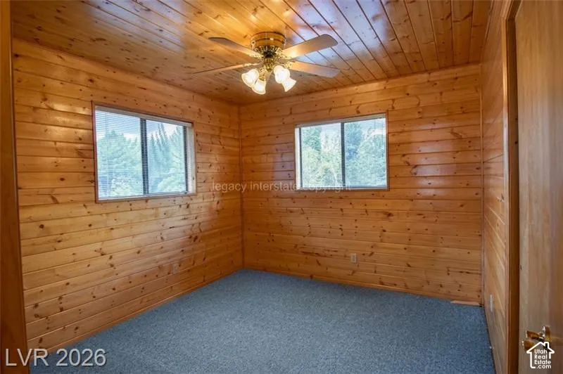 Wood-paneled walls and ceiling featuring two windows with horizontal blinds
