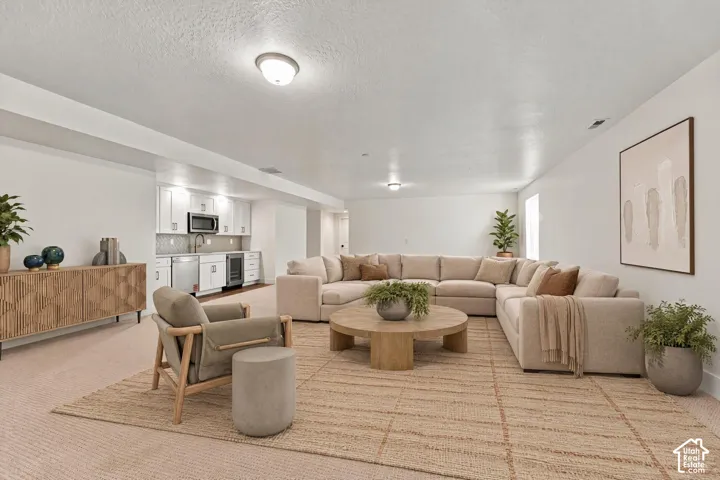 Open floor plan featuring wall-to-wall carpeting and a kitchenette equipped with white cabinetry, stainless steel appliances, and a tiled backsplash
