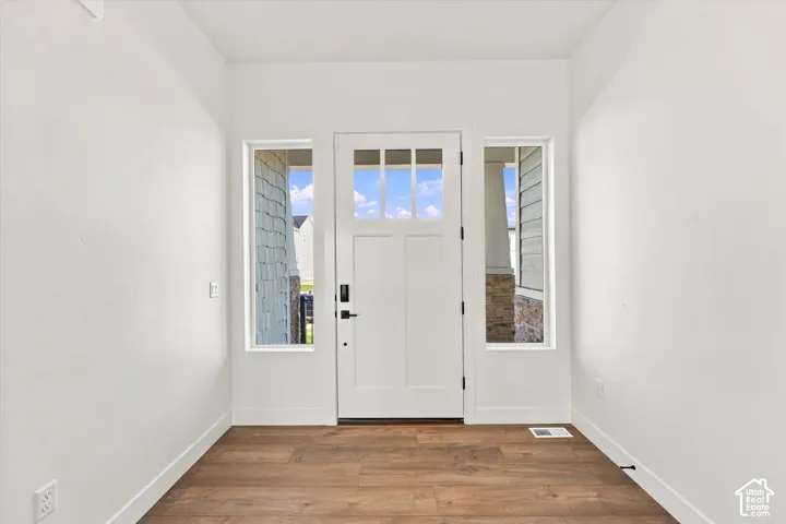 Wood-finish flooring, white walls, and a white front door with multiple glass panes