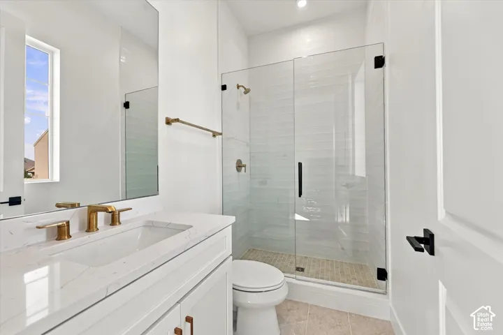 White vanity with a stone countertop and gold-finish fixtures