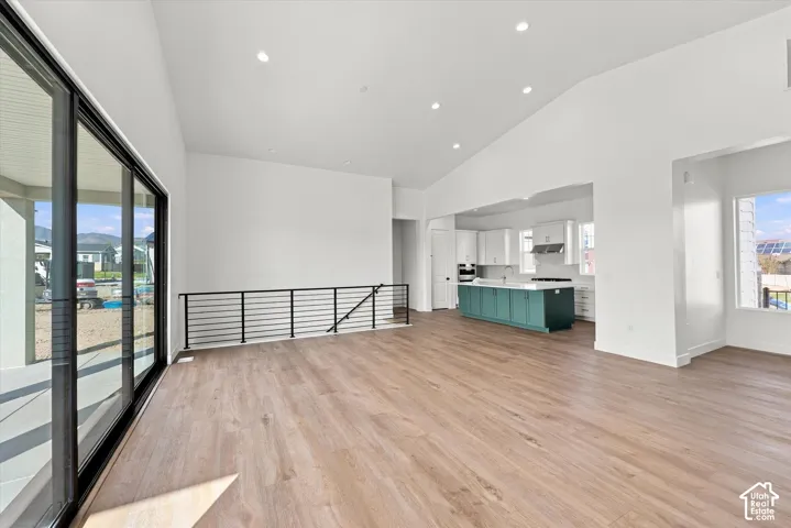 Vaulted ceilings, wood-finish flooring, sliding glass patio doors, kitchen with a central island and white cabinetry