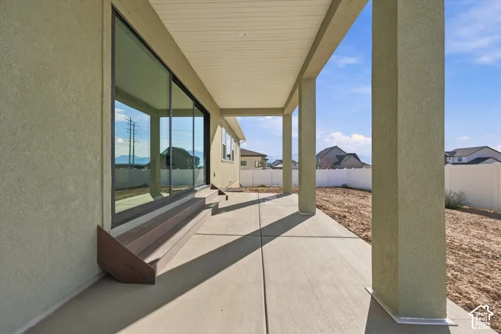 Covered patio with concrete flooring, multiple support columns, and an integrated multi-level composite deck