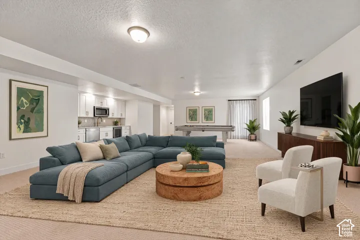 Spacious recreational room featuring recessed lighting, a built-in wet bar with stainless steel appliances, and durable carpet flooring throughout