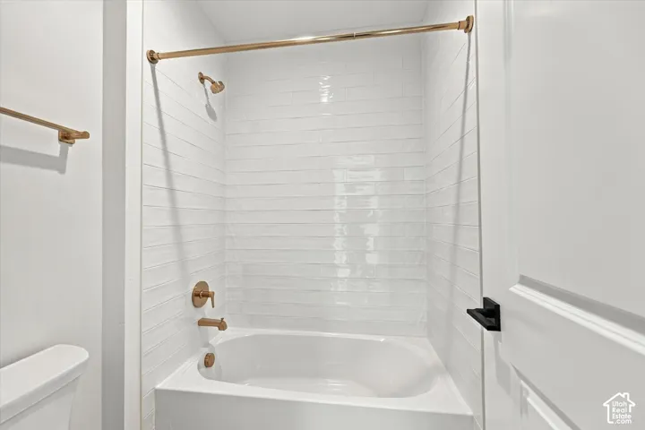 Bathtub with white subway tile surround, bronze-finish fixtures, and a coordinating bronze-finish towel bar