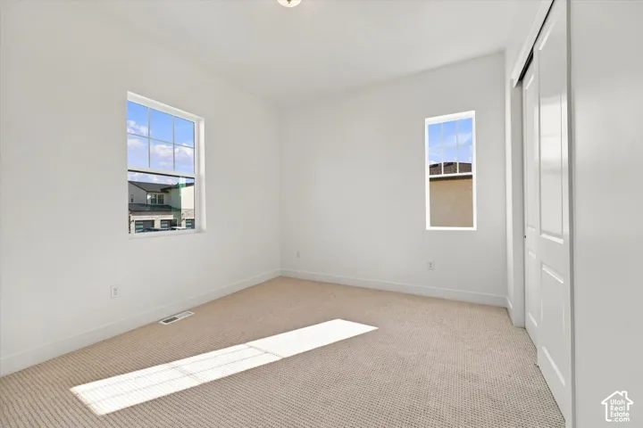 Neutral-toned carpeting, white walls, and two distinct windows