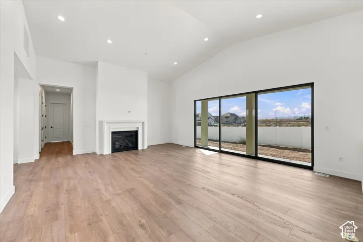 Vaulted ceilings, wood-finish flooring, recessed lighting, built-in fireplace, and expansive sliding glass doors