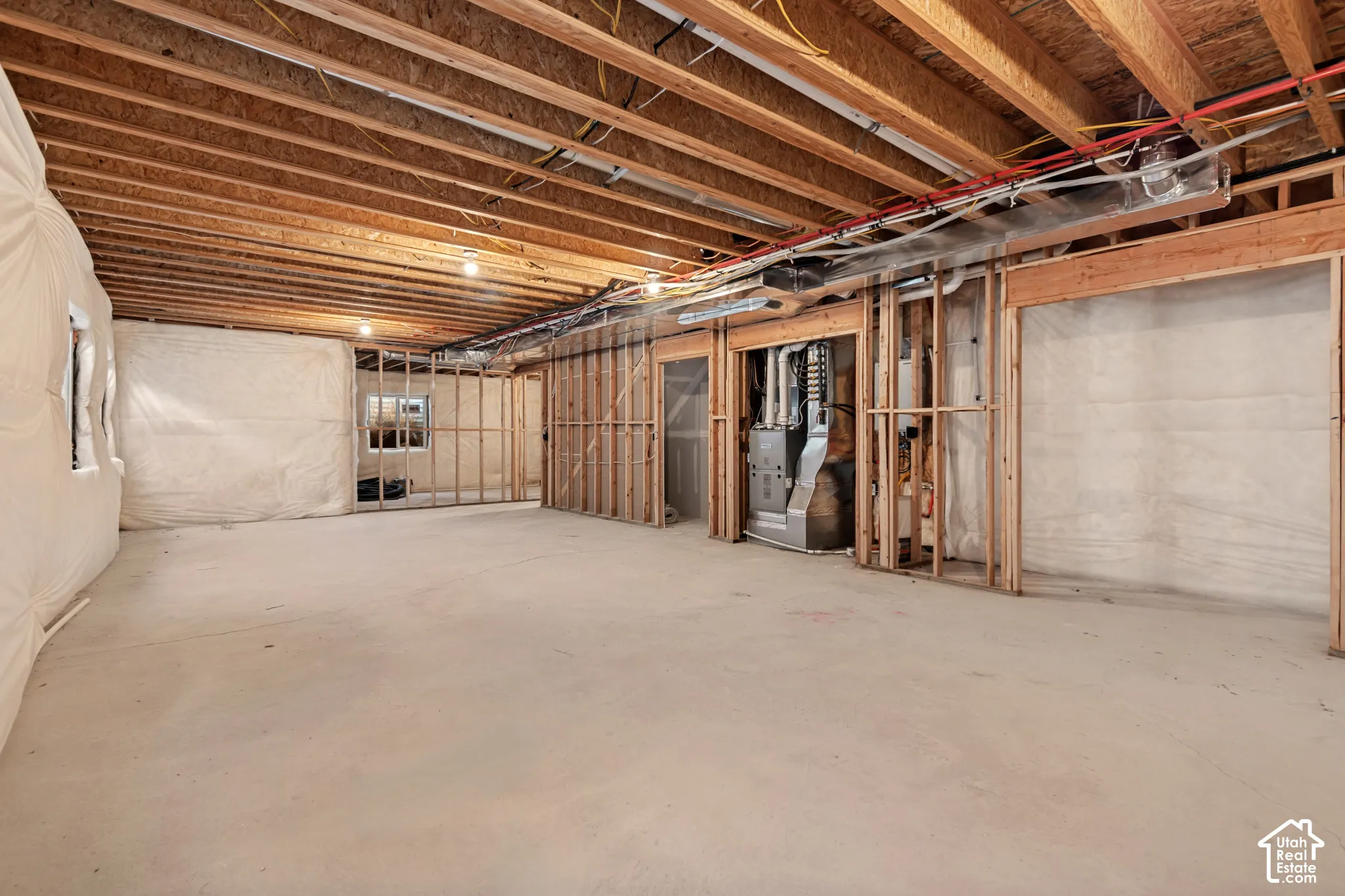 Unfinished basement with exposed ceiling joists, concrete flooring, and framed interior walls