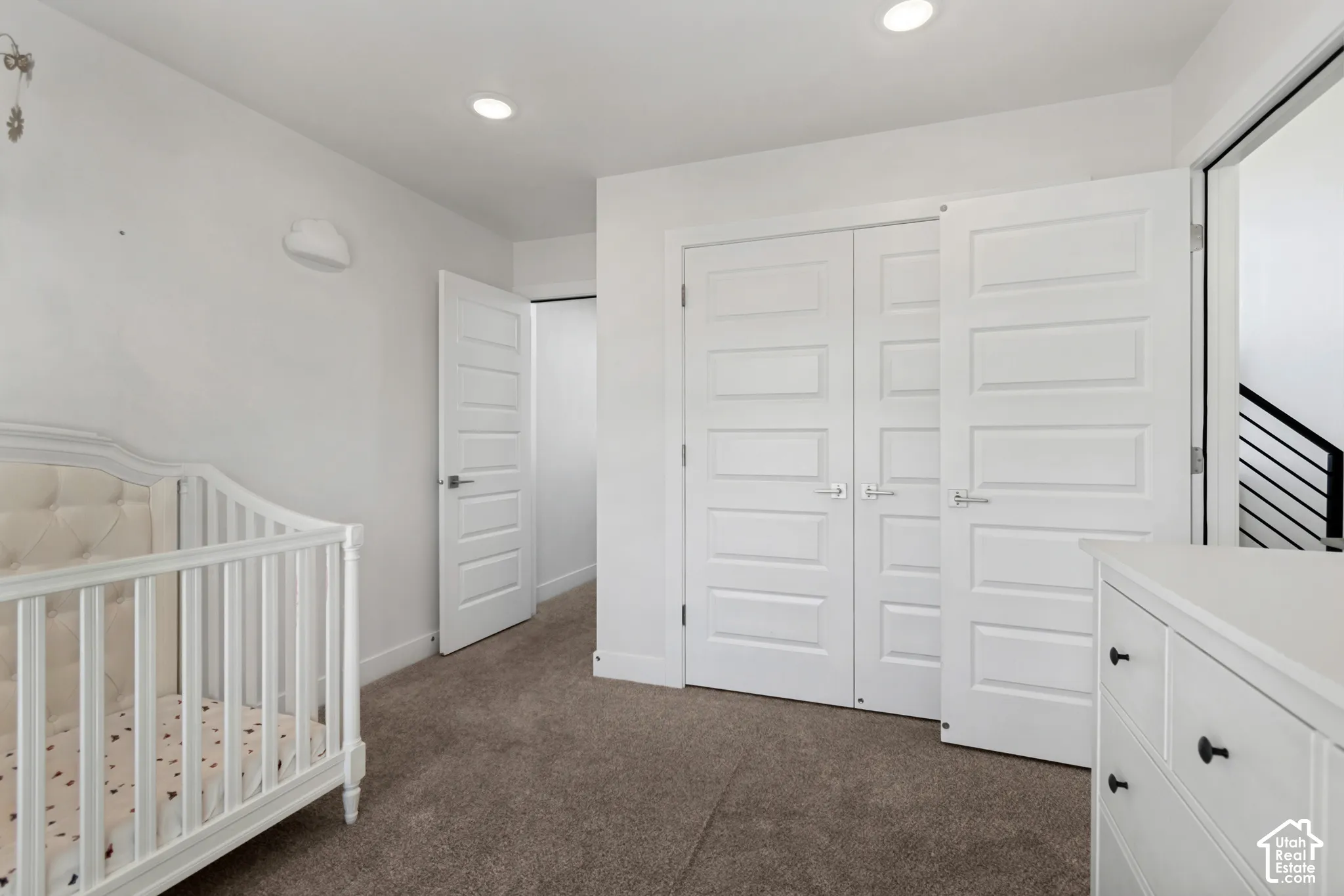 Recessed lighting, neutral carpeting, contemporary paneled doors, and white walls