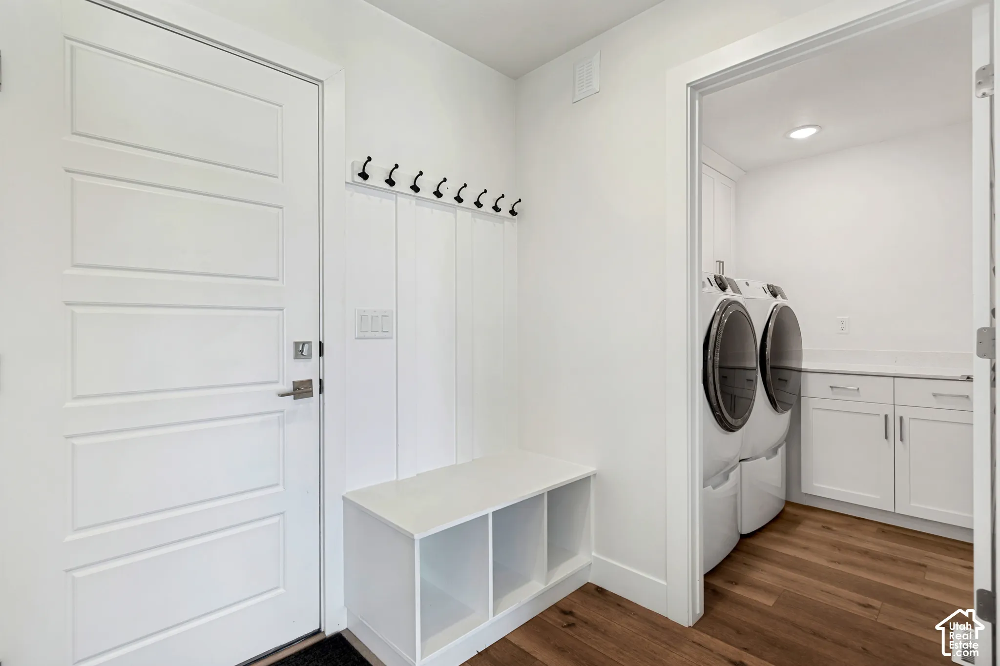 Entryway with a built-in bench and coat hooks, featuring wood-finish flooring