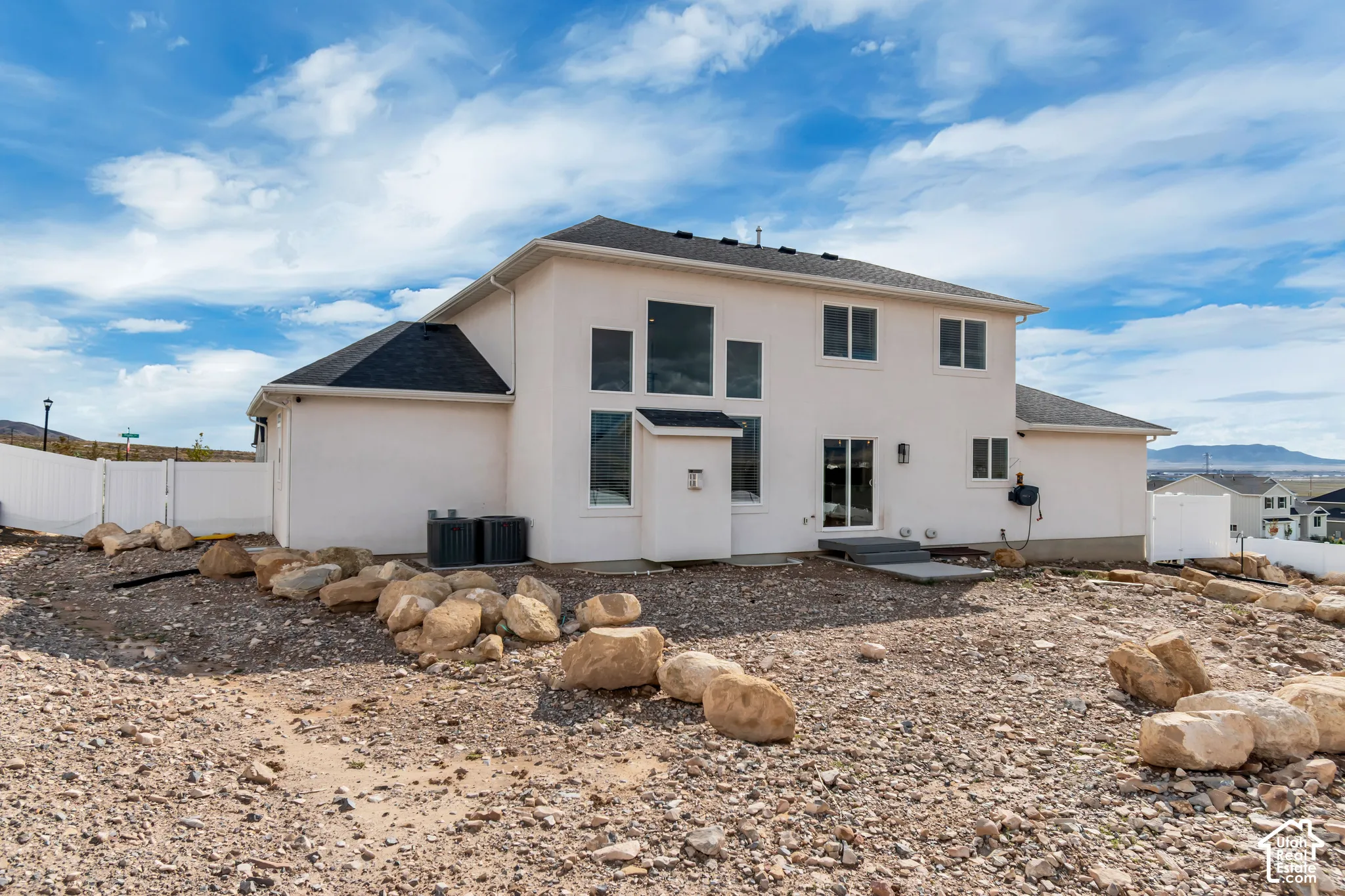 White stucco exterior with multiple windows, black roof, and rear sliding glass door