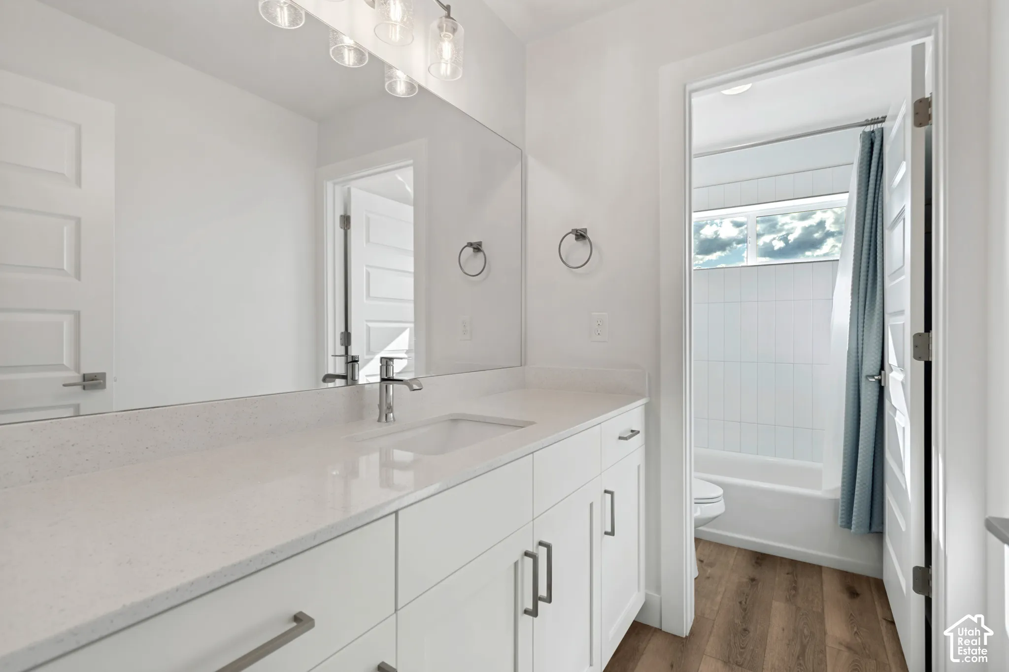 Double vanity with integrated sinks, chrome fixtures, and a multi-bulb light fixture