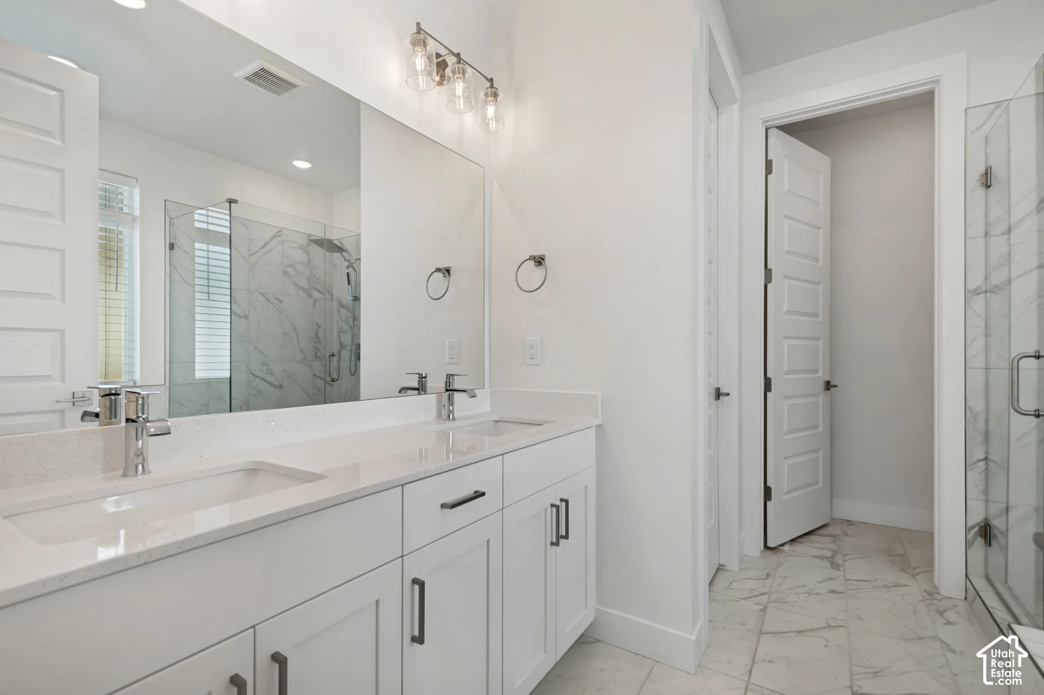 Double vanity with integrated sinks, contemporary chrome faucets, and white shaker-style cabinetry