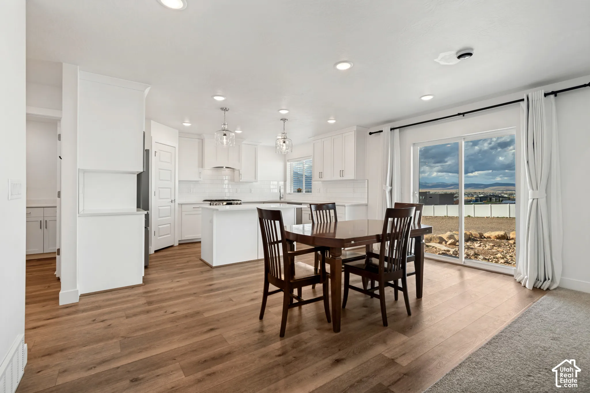Open-concept living space featuring wood-finish flooring, recessed lighting, and a sliding glass door