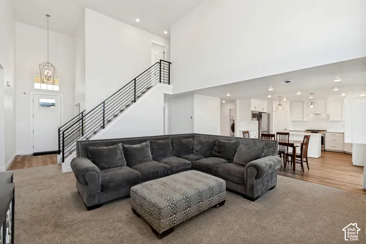 Vaulted ceilings, open concept design, contemporary staircase with black metal railing, wood-finish flooring, and recessed lighting