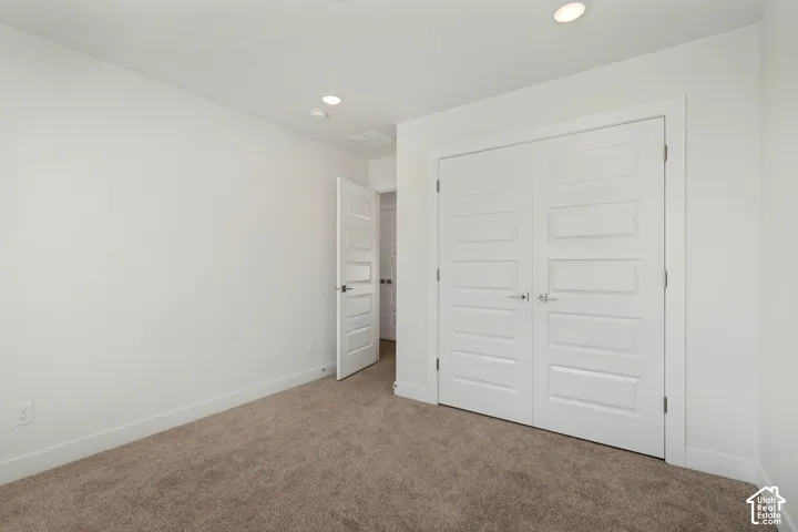 Plush carpeting, recessed lighting, and white walls
