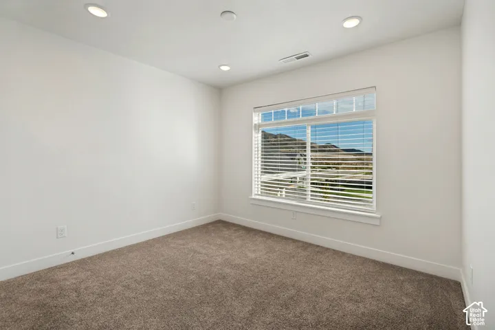 Recessed ceiling lighting, white painted walls, carpet flooring, window with horizontal blinds, and mountain scenery