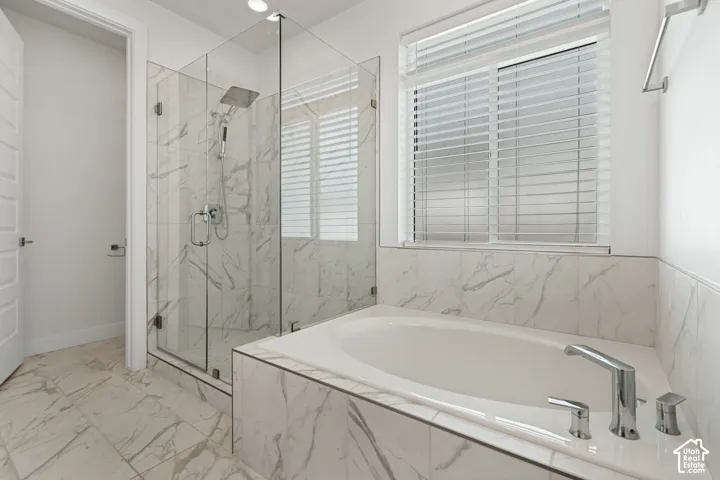 Glass-enclosed shower with a rainfall showerhead, white soaking tub, and tile surround, all featuring a white and gray veined pattern