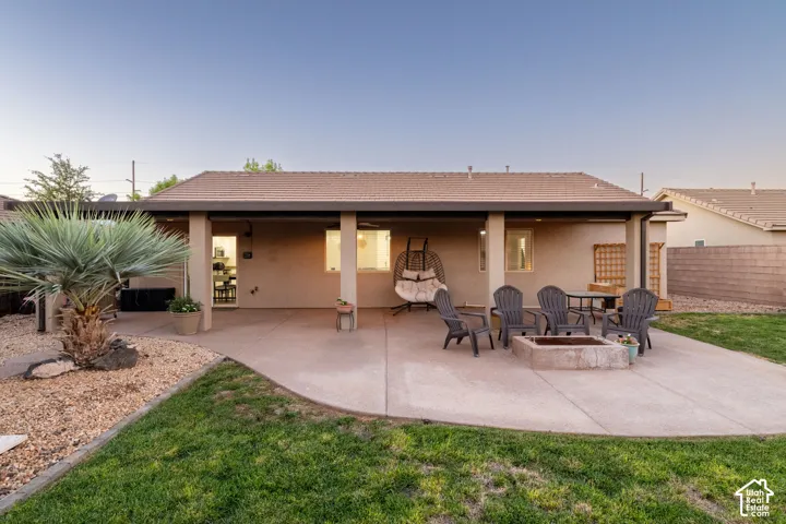 Expansive concrete patio with a built-in fire pit, covered patio area, and xeriscaped planting beds