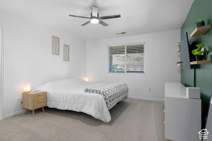 Wall-to-wall carpeting, ceiling fan with integrated lighting, and a window with blinds