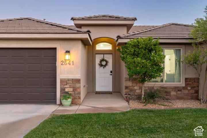 Stucco exterior with stone veneer accents, an attached two-car garage, and a covered entryway