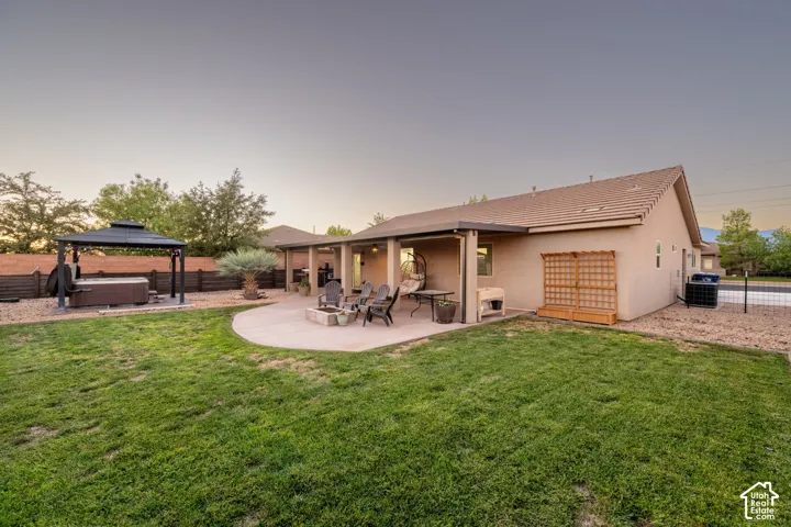 Expansive backyard featuring a manicured lawn, concrete patio, covered patio area, and a separate gazebo