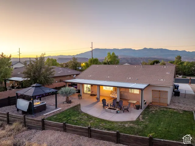 Expansive backyard featuring a covered patio, an additional patio with a fire pit, and a hot tub with a gazebo