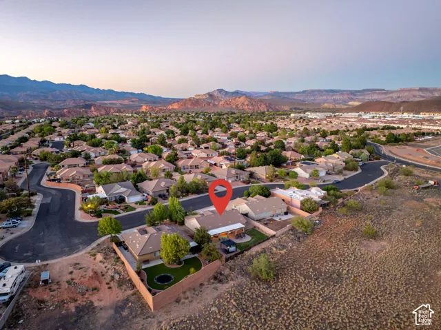 Expansive neighborhood setting with numerous residential properties, abundant green landscaping, and distant mountain backdrops