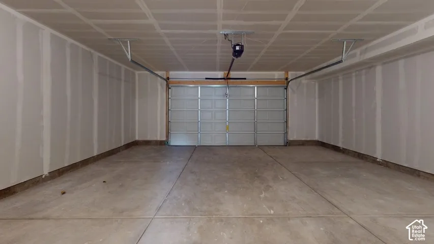 Concrete flooring, unfinished drywall, overhead garage door, automatic garage door opener, overhead lighting track