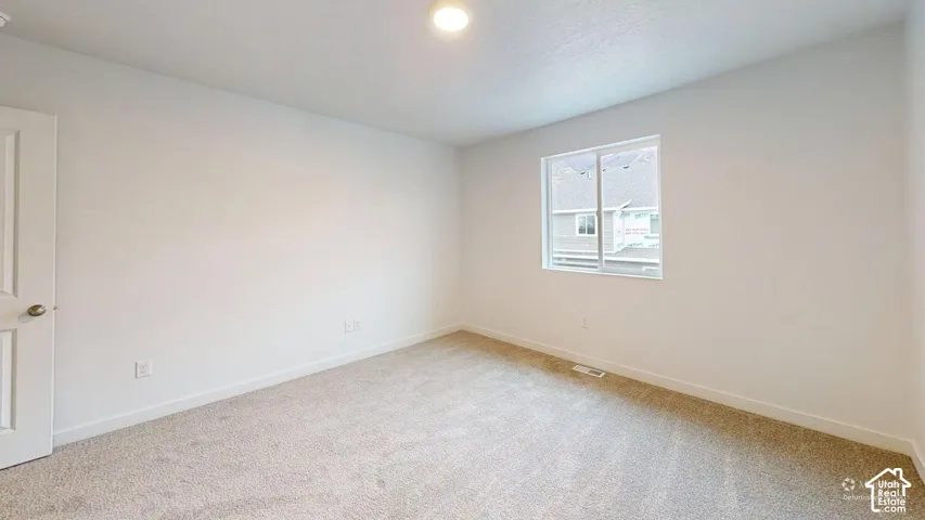 Recessed ceiling light, neutral carpeting, white interior door with brass hardware, and a single-pane window
