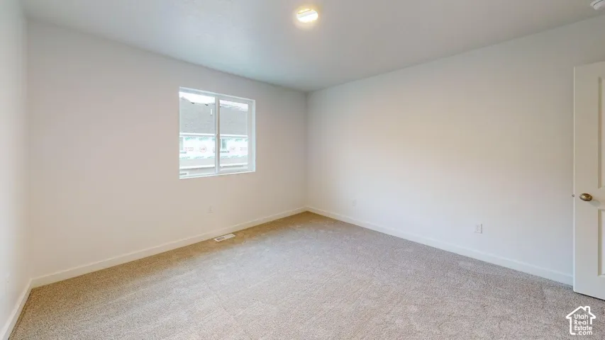 Recessed lighting, light-colored carpeting, and a window with white trim