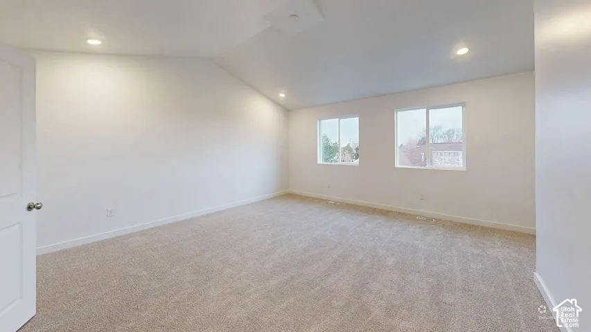 Vaulted ceiling, recessed lighting, neutral carpet, two windows, and white walls