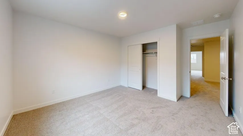 Neutral tone wall paint, light neutral carpeting, recessed lighting, and a closet with sliding doors