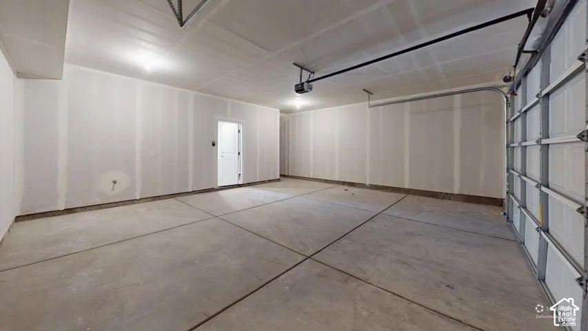 Attached garage space with a concrete floor, overhead lighting, and an automatic garage door opener